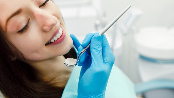 Procedimento de profilaxia dentária em andamento, instrumentos odontológicos de precisão, higienista dental com equipamentos modernos, ambiente clínico sofisticado bege claro, iluminação técnica profissional, foco em prevenção e cuidado, fotografia clean e acolhedora, paleta em tons neutros e dourado suave