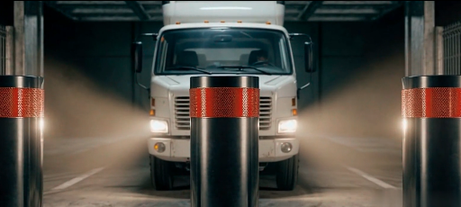Caminhão branco em túnel industrial sendo bloqueado por bollards automáticos cromados com faixas refletivas laranja, iluminação dramática com farol frontal aceso, paleta preto profundo com detalhes em laranja metálico, ângulo cinematográfico frontal simétrico, fotografia ultra-realista 8k